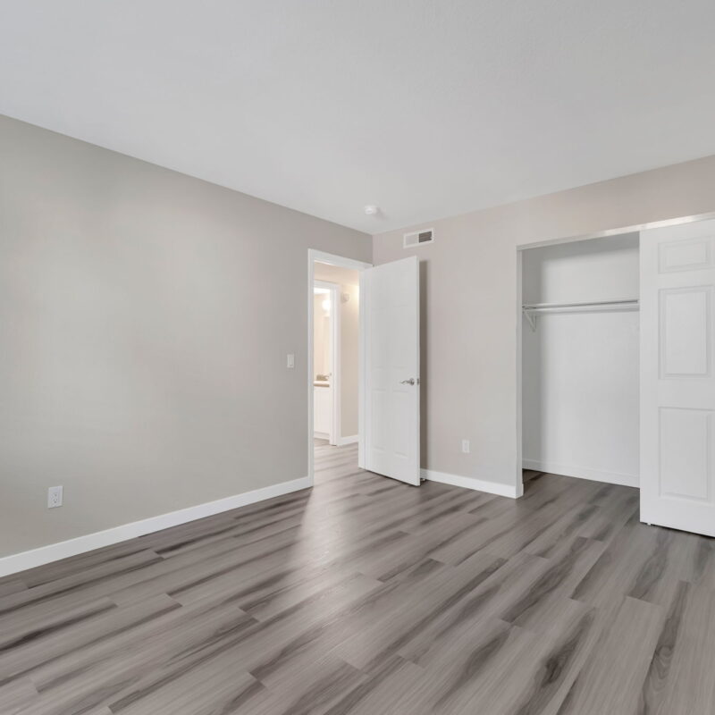 Empty room with wood flooring and open closet.