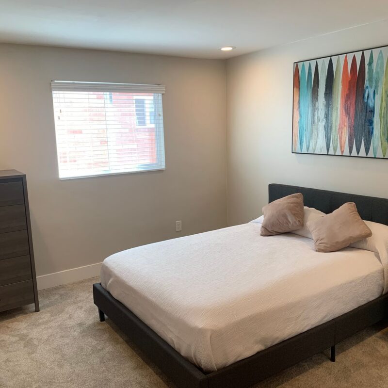 Modern bedroom with bed, dresser, and abstract art