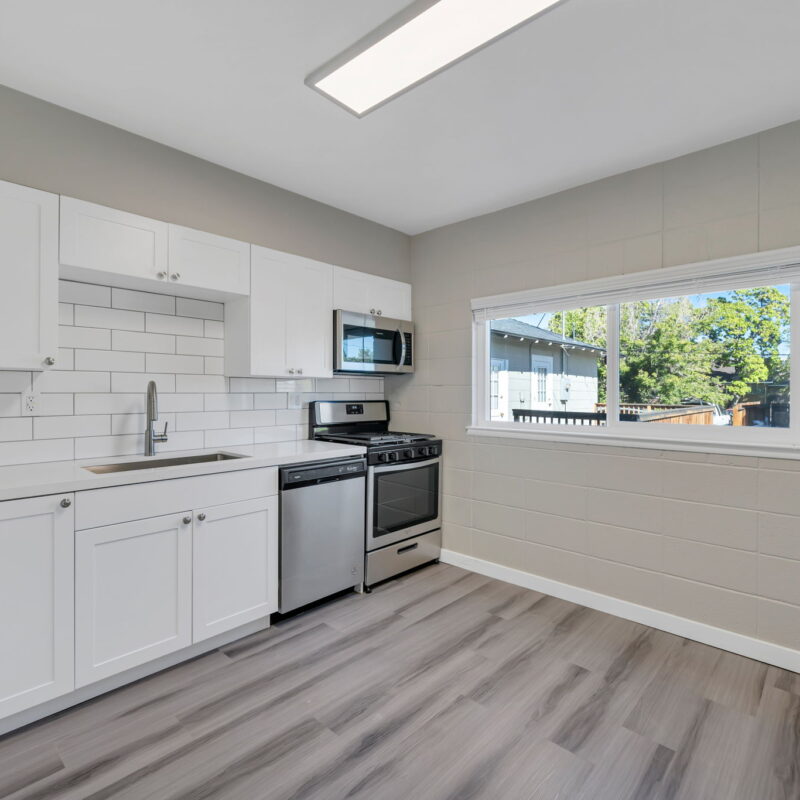 Modern kitchen with white cabinets and stainless appliances.