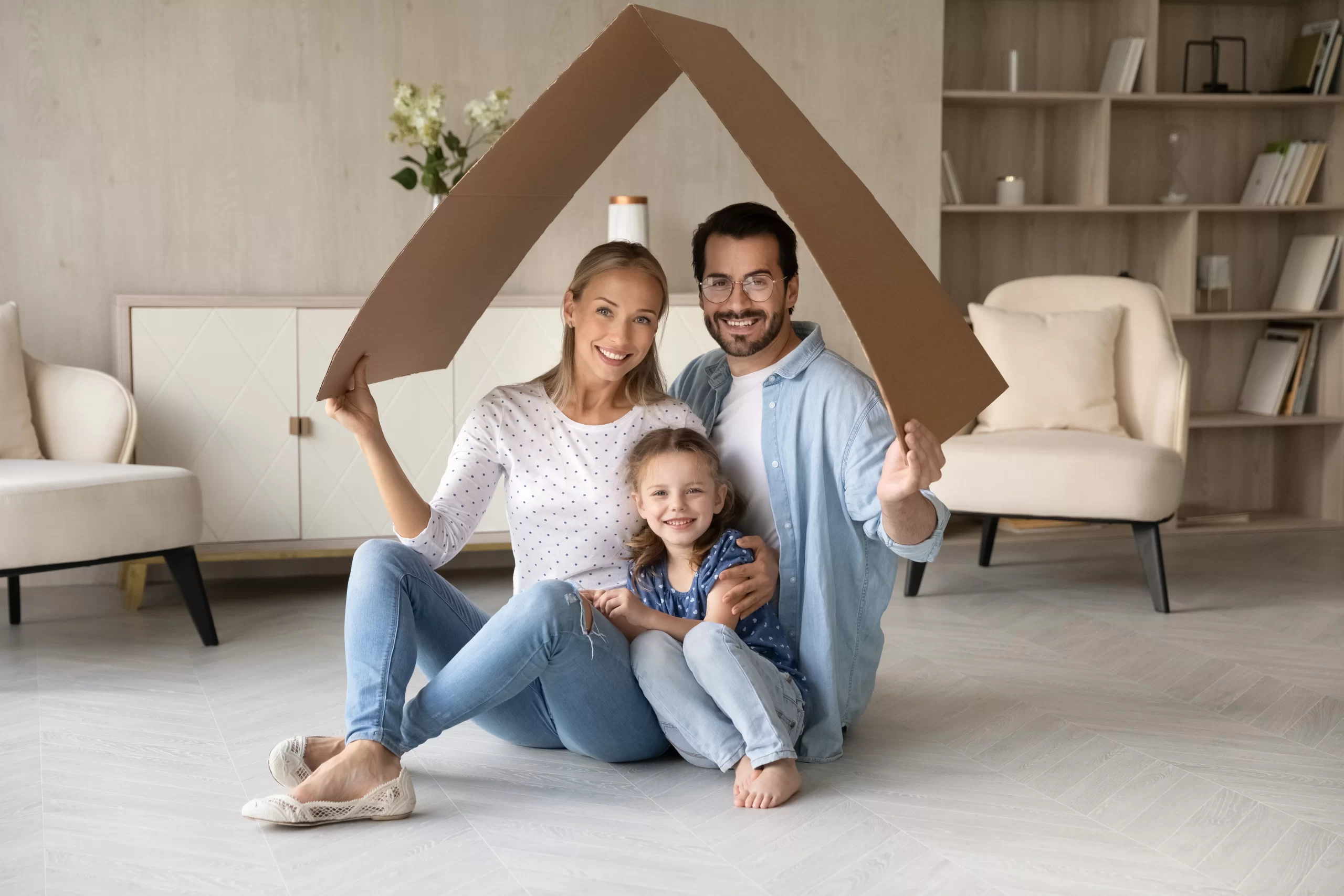 Happy family holding cardboard roof indoors.