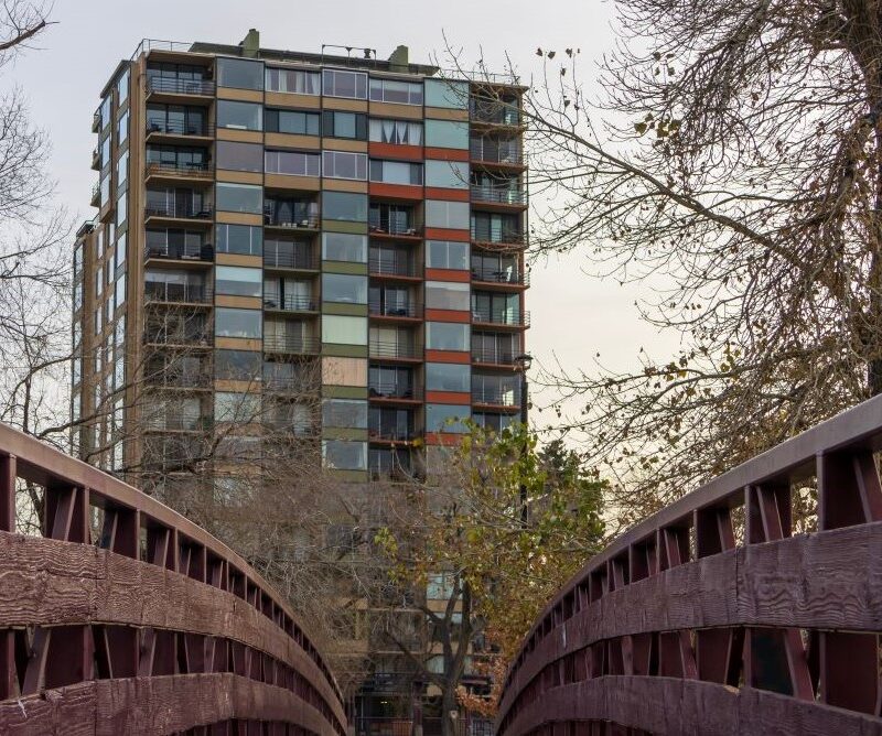 Colorful building behind a wooden bridge with trees